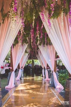 an outdoor wedding venue with pink and white draping, flowers and greenery