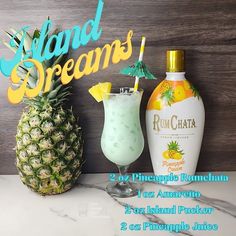 two pineapples and a drink sit on a counter next to a sign that says island dreams