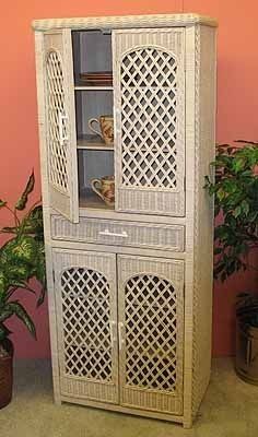 a white wicker cabinet sitting next to a potted plant