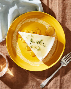 a yellow plate topped with food next to a glass of wine and a silver fork