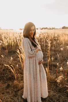 a pregnant woman standing in the middle of a field