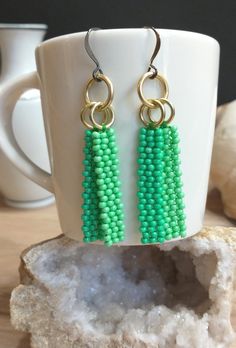 "Minimalist beaded earrings with a tropical sea green color theme. These simple bar earrings were made using the brick stitch method to create two dangle bars per earring with tiny green toned Czech glass seed beads. The stitches are reinforced, and the ends are finished with thread sealant to create a long lasting tight weave. The beaded dangles are then attached to polished gold aluminum rings and stainless steel French hook earwires (hypoallergenic, perfect for those with metal allergies). Th Cheap Green Earrings With Colorful Beads, Green Bohemian Earrings For Everyday Wear, Green Bohemian Earrings For Everyday, Everyday Green Round Bead Earrings, Green Bohemian Beaded Earrings For Everyday, Everyday Green Round Beaded Earrings, Bohemian Green Beaded Earrings For Everyday, Nickel-free Green Beaded Earrings For Beach, Green Rectangular Bohemian Earrings