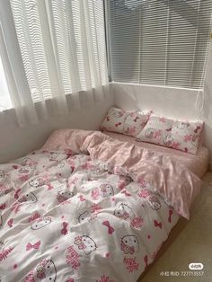 a bed with hello kitty sheets and pink comforter in front of a white window