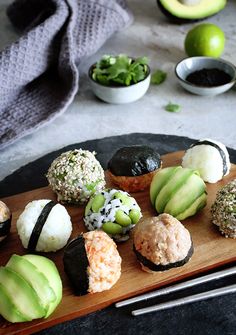 an assortment of sushi on a wooden cutting board