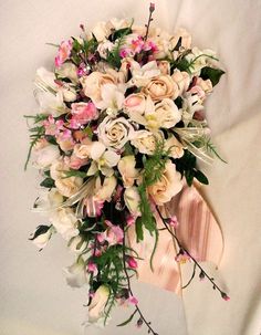 a bridal bouquet with pink and white flowers on a beige ribbon tied around it