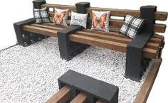 a wooden bench sitting on top of a pile of gravel next to two black benches