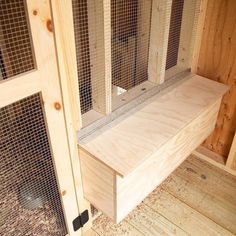 the inside of a chicken coop with wooden flooring and wire mesh doors on each side