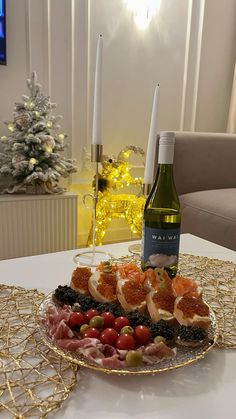 a platter filled with meats and vegetables next to a bottle of wine on a table