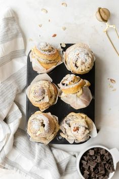 several muffins on a tray with powdered sugar and chocolate chips next to them