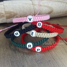 four bracelets with words written on them sitting on a wooden table next to a pillow