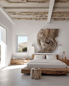 a bedroom with white walls and flooring has a large piece of driftwood on the wall