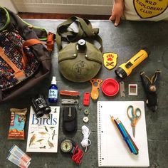 the contents of a backpack are laid out on the floor next to some school supplies