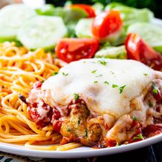 a white plate topped with pasta and meat covered in sauce next to veggies