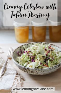 a white bowl filled with coleslaw next to two jars of jelly and orange juice