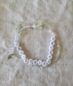 a white beaded bracelet with the word baby spelled in small beads on a beige cloth