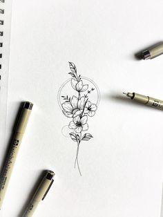 some pens are laying on top of a piece of paper with flowers drawn on it