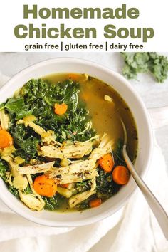 a bowl of chicken soup with carrots and spinach in it, on top of a white cloth