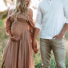 a pregnant woman standing next to a man in a field