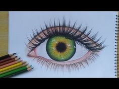 a drawing of an eye with colored pencils next to it on top of a table