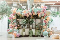 a room filled with lots of balloons and potted plants