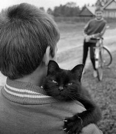 a man holding a black cat in his arms with an image of a boy on the back