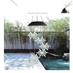 a wind chime with snowflakes hanging from it's sides next to a swimming pool