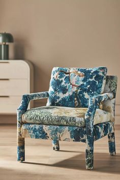 a blue and white chair sitting on top of a wooden floor next to a dresser