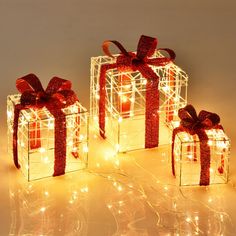 three wrapped presents with red bows and lights