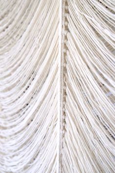 the back side of a white wall hanging from a rope structure with strings attached to it