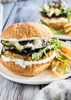 a sandwich with lettuce, cheese and other toppings on a plate next to french fries