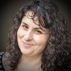 a woman with curly hair smiling at the camera