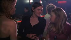 three young women talking to each other in a bar