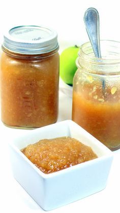 two jars filled with apple jam next to an apple