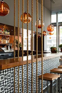 a bar with wooden stools and hanging lights