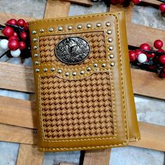 a brown leather wallet sitting on top of a wooden bench next to red berries and beads