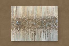 an abstract painting with gold and silver glitters on the side of a tan wall