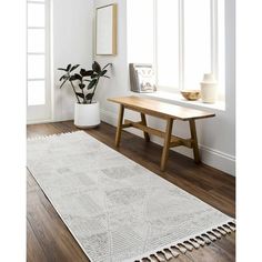 a white rug with fringes on the floor in front of a table and window