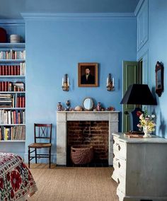 a bedroom with blue walls and a fireplace in the corner, surrounded by bookshelves