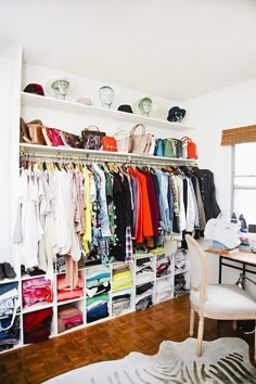 an organized closet with lots of clothes and handbags on shelves, along with a desk