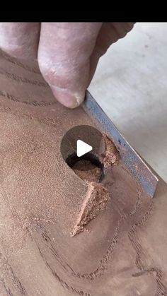 a person is using a knife to cut something out of the ground with sand on it