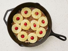 pineapples and cherries are arranged in a skillet