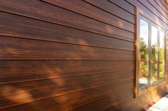 the side of a house with wood siding on it's sides and glass windows