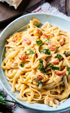 pasta with shrimp and parsley in a blue bowl on top of a wooden table