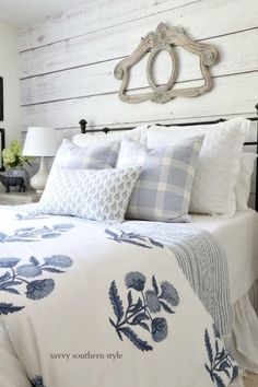 a bed with blue and white comforter in a bedroom next to a wall mounted mirror