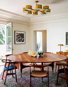 a dining room table with chairs and a chandelier hanging from the ceiling above it