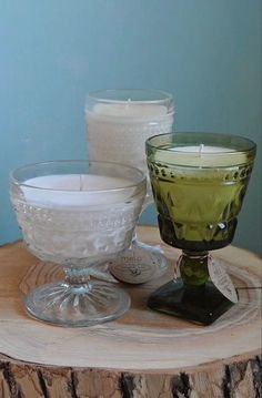 three glass candles sitting on top of a wooden table