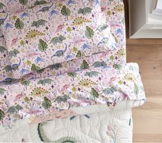 a close up of a bed with a pink and green floral comforter on it