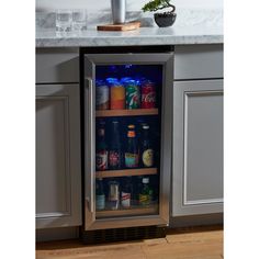 an open refrigerator with drinks in it sitting on the floor next to a kitchen counter