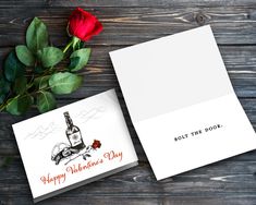 an open card with a bottle of wine and a red rose on the wooden table