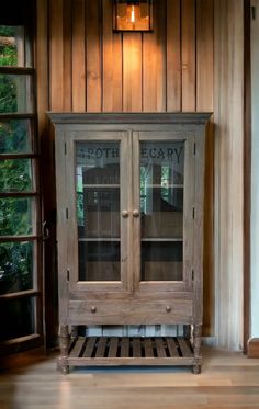 an old wooden cabinet with glass doors on the front and bottom, in a wood paneled room